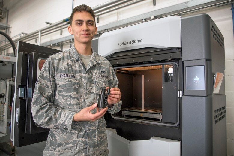 U.S. Air Force Staff Sgt. Montana Engelking, 100th Maintenance Squadron aircraft metals technology welder machinist, holds a 3D printed example at RAF Mildenhall, England [Source:  U.S. Air Force ]