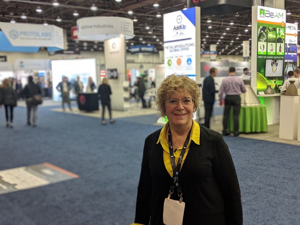  Debra Wilcox, CEO of Accucode 3D, surrounded by 3D printing companies at RAPID + TCT 2019 [Image: Fabbaloo] 