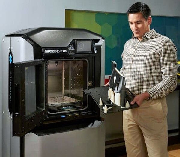3D printer operator removing completed 3D prints from an F370 device [Source: Stratasys]