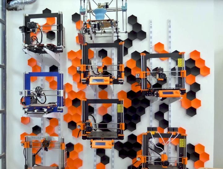  Prusa Research’s all-time product line on display at their HQ, including the current Original Prusa i3 MK3 printer [Source: YouTube] 