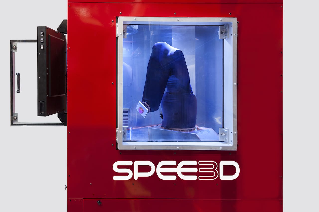  A view inside Spee3D's LIGHTSPEE3D 3D metal printer, showing a shroud around the robot arm to protect it from stray supersonic metal particles 