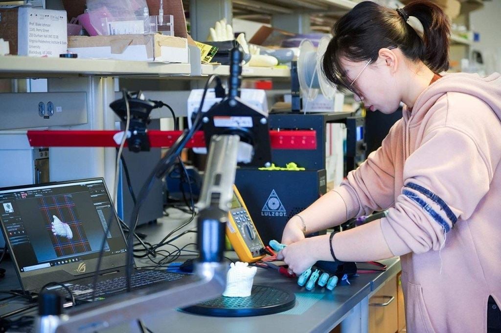  Yuxin Tong, an industrial and systems engineering graduate student, adjusts a 3D printed prosthetic. Tong was first author of a newly published research study about integrating electronic sensors in personalized 3D printed prosthetics. [Image: Linda Hazelwood/Virginia Tech] 